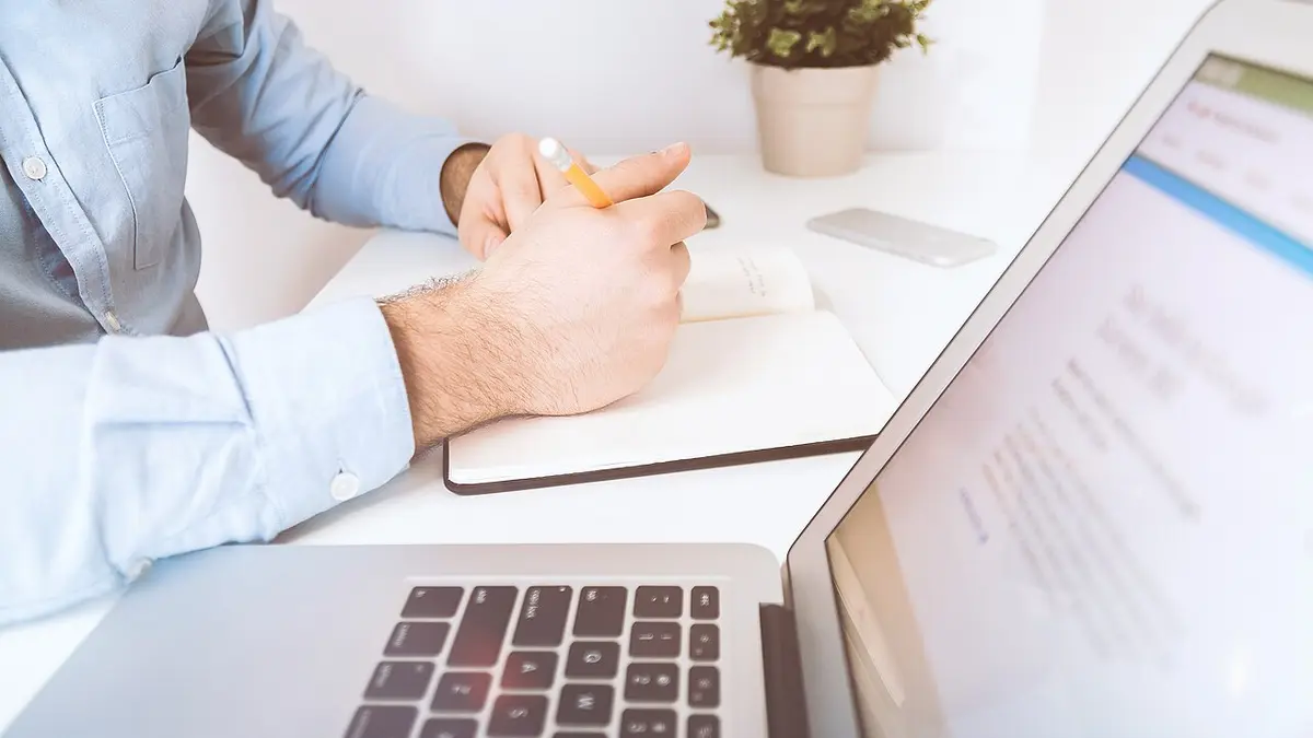 A professional working with a laptop and handwritten notes